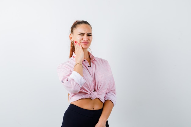 Young female suffering from toothache in casual shirt and looking unwell. front view.