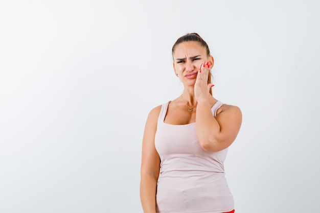 Free photo young female suffering from toothache in singlet and looking unwell. front view.