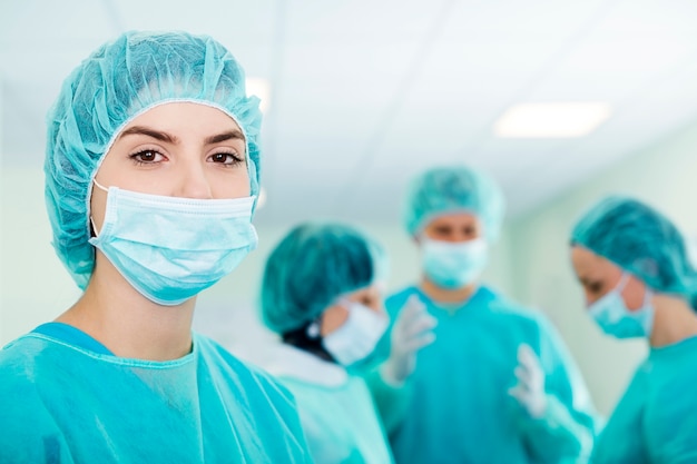 Young female surgeon with medical team in back before surgery