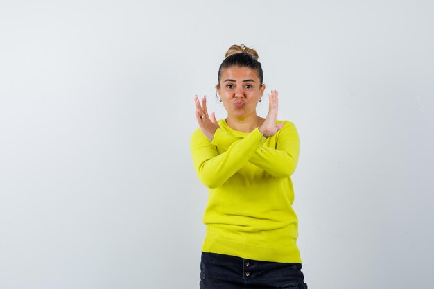 Young female in sweater, denim skirt showing stop gesture and looking confident 
