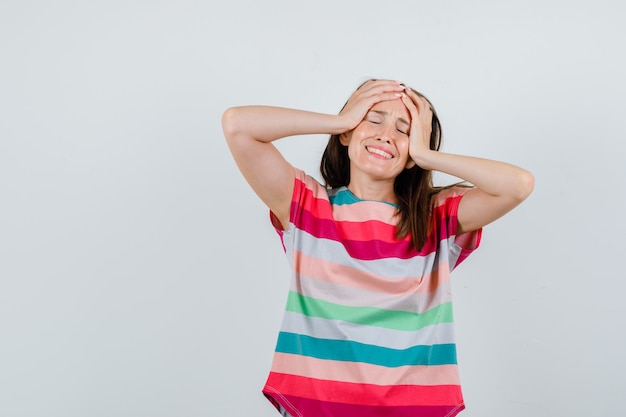 Free photo young female in t-shirt holding hands on head and looking annoyed , front view.