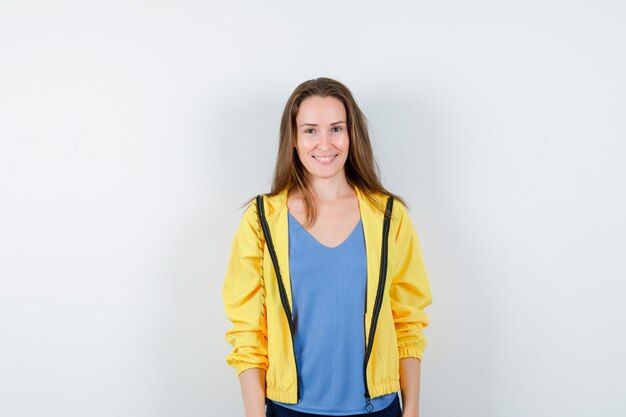 Young female in t-shirt, jacket looking at camera and looking cheerful, front view.