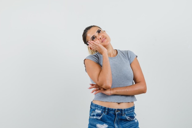 Young female in t-shirt, shorts looking up and looking thoughtful