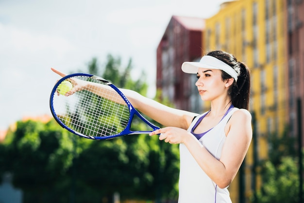 Young female tennis player holding racket pointing at something