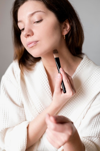 Young female using brush for foundation