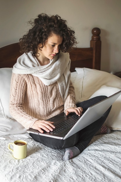 Free photo young female using laptop on bed