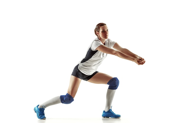 Free photo young female volleyball player isolated on white wall. woman in sport's equipment and shoes or sneakers training and practicing. concept of sport, healthy lifestyle, motion and movement.