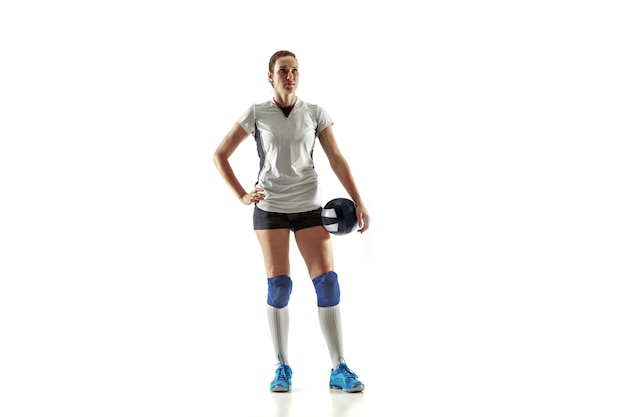 Young female volleyball player isolated on white wall. Woman in sport's equipment and shoes or sneakers training and practicing. Concept of sport, healthy lifestyle, motion and movement.