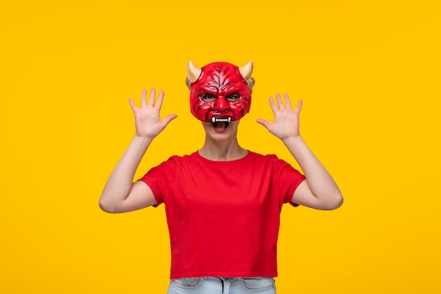 Молодая женщина в страшной маске дьявола на желтом фоне мультяшный хэллоуин
