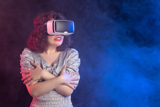 Young female wearing virtual reality headset on dark blue surface