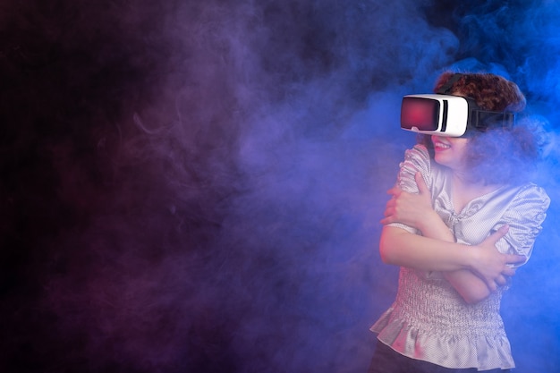 Young female wearing virtual reality headset on dark blue surface