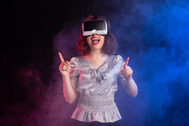 Young female wearing virtual reality headset on dark blue surface