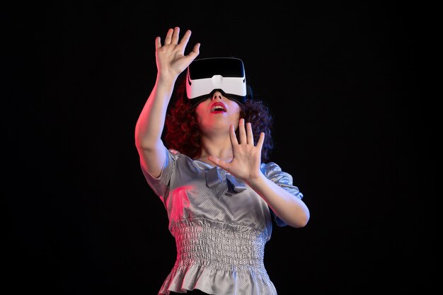 Young female wearing virtual reality headset on a dark surface