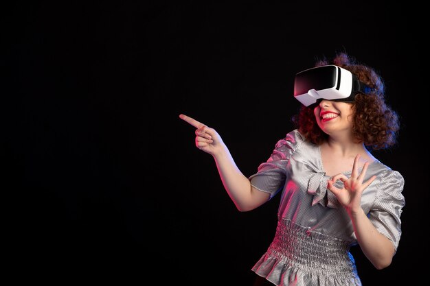 Young female wearing virtual reality headset on dark surface