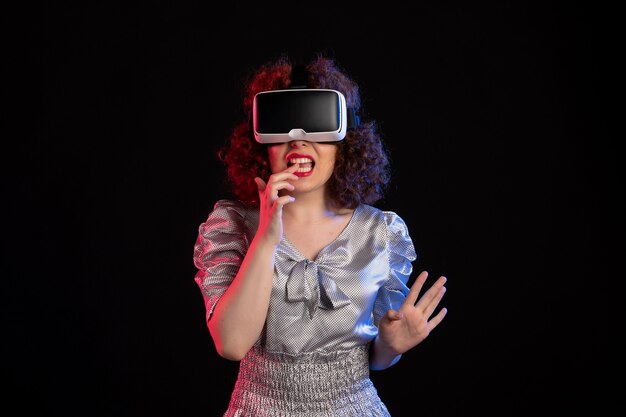 Young female wearing virtual reality headset on dark surface