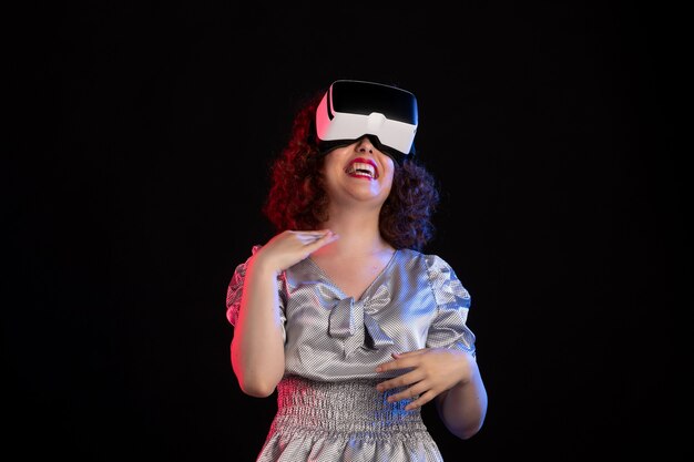 Young female wearing virtual reality headset on dark surface