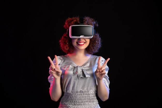 Young female wearing virtual reality headset on dark surface