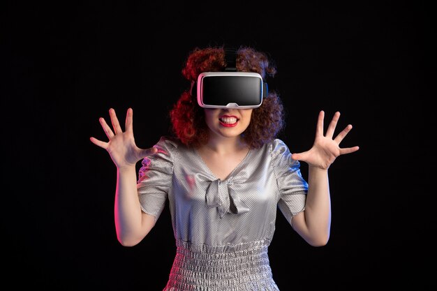 Молодая женщина в гарнитуре виртуальной реальности на темной поверхности