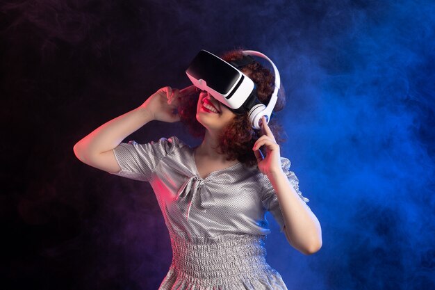 Young female wearing vr headset in headphones on dark blue surface