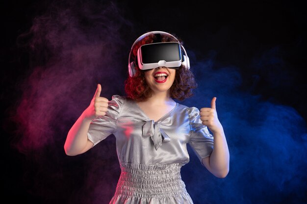 Young female wearing vr headset in headphones on dark surface