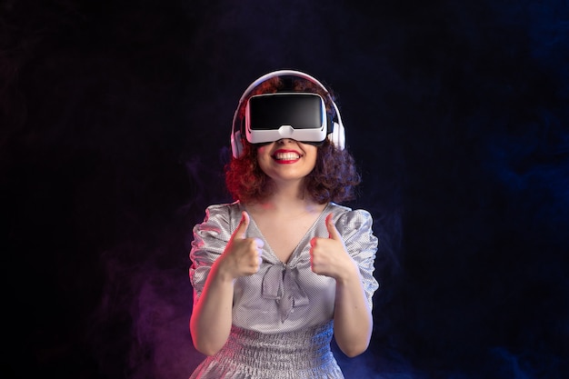 Young female wearing vr headset in headphones on dark surface