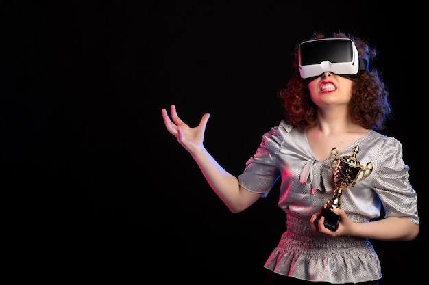 Young female wearing vr headset with cup on dark surface