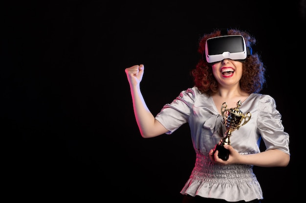 Free photo young female wearing vr headset with cup on dark surface