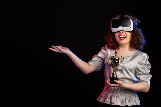Young female wearing vr headset with cup on dark surface