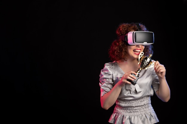 Young female wearing vr headset with cup on dark surface