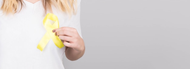 Young female in white t-shirt holding yellow ribbon awareness symbol for suicide