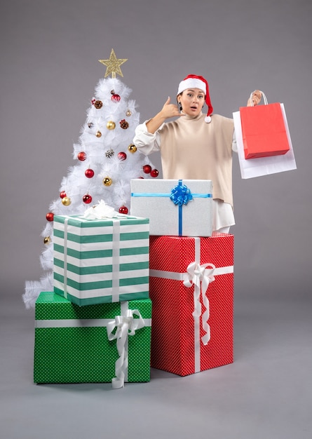 young female with christmas presents on grey