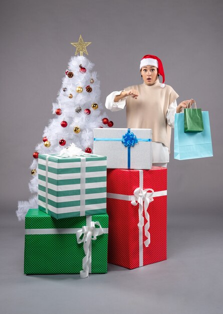 young female with christmas presents on light floor