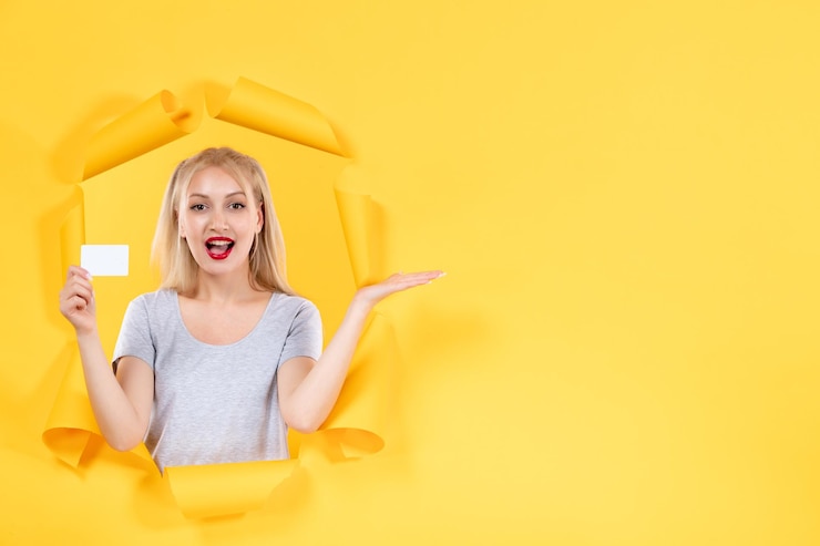 Бесплатный Фотография молодая женщина с кредитной картой на желтом фоне распродажа денег на лице