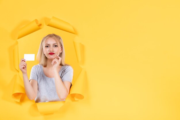 Young female with credit card on yellow background facial sale shopping