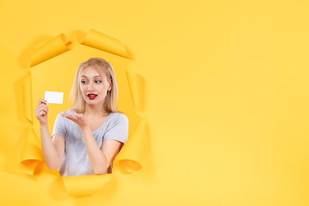 Giovane donna con carta di credito su sfondo giallo acquisto di vendita di denaro Foto Gratuite