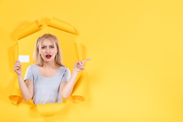 Young female with credit card on yellow background sale shopping facial