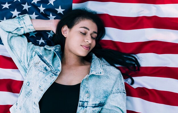 Free photo young female with eyes closed lying on american flag