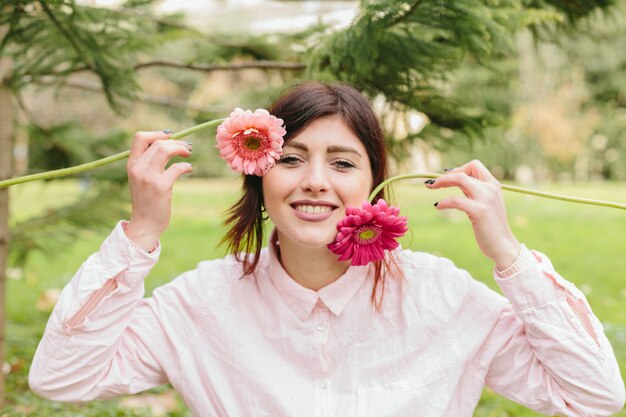 顔の近くの花を持つ若い女性