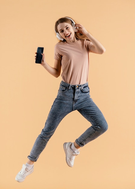 Free photo young female with headphones and mobile jumping