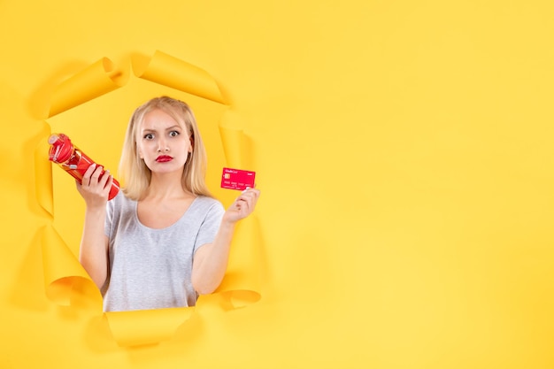 Young female with red bottle and credit card on yellow background sport athlete gym money sale