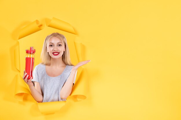 Young female with red bottle on a yellow background facial fit sport athlete gym