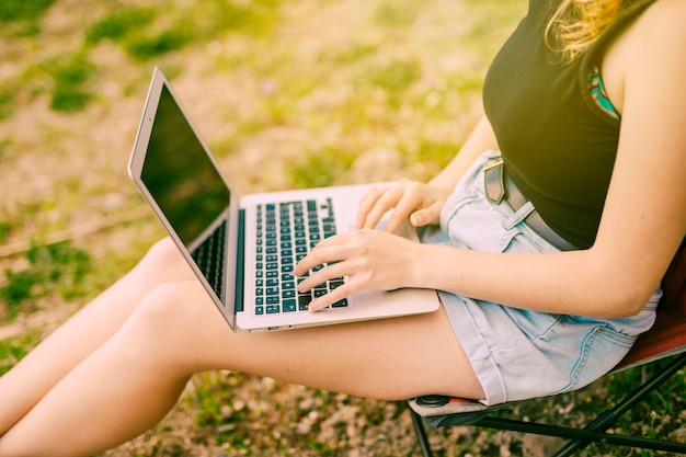 Молодая женщина работает на ноутбуке в лесу