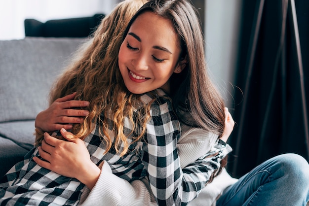 Young females embracing while sitting on floor