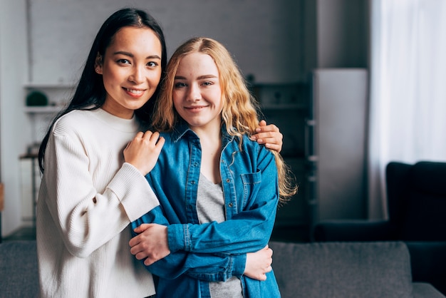 Young females hugging by shoulders