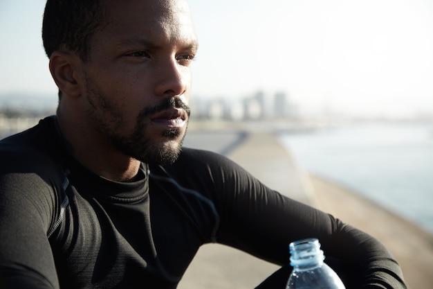 Free photo young fit man at the beach drinking water