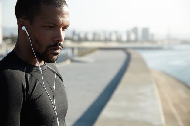 Young fit man at the beach listening to music