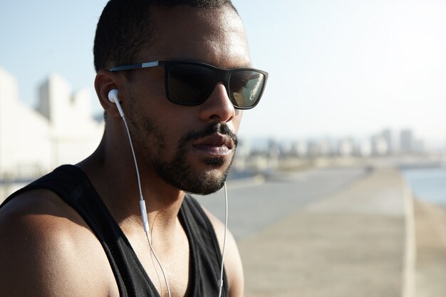 Young fit man at the beach wearing sunglasses