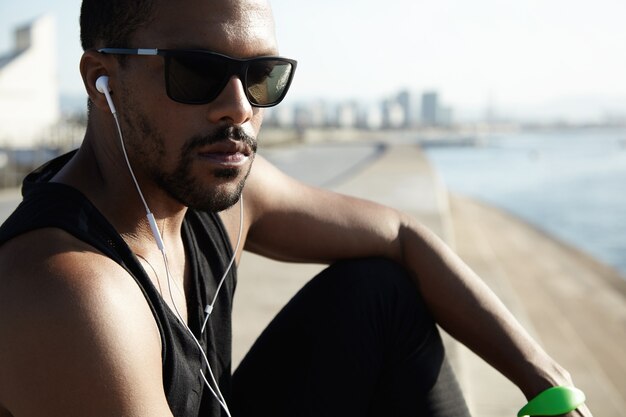 Young fit man at the beach wearing sunglasses