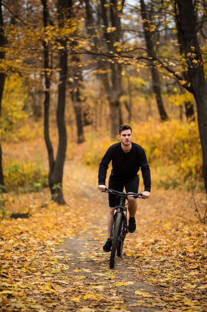 가을 공원에서 화창한 날에 자전거를 타는 동안 젊은 맞는 남자