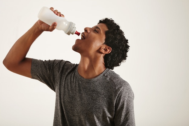Free photo young fit smiling black man drinking water from a sports bottle, mouth wide open, isolated on white